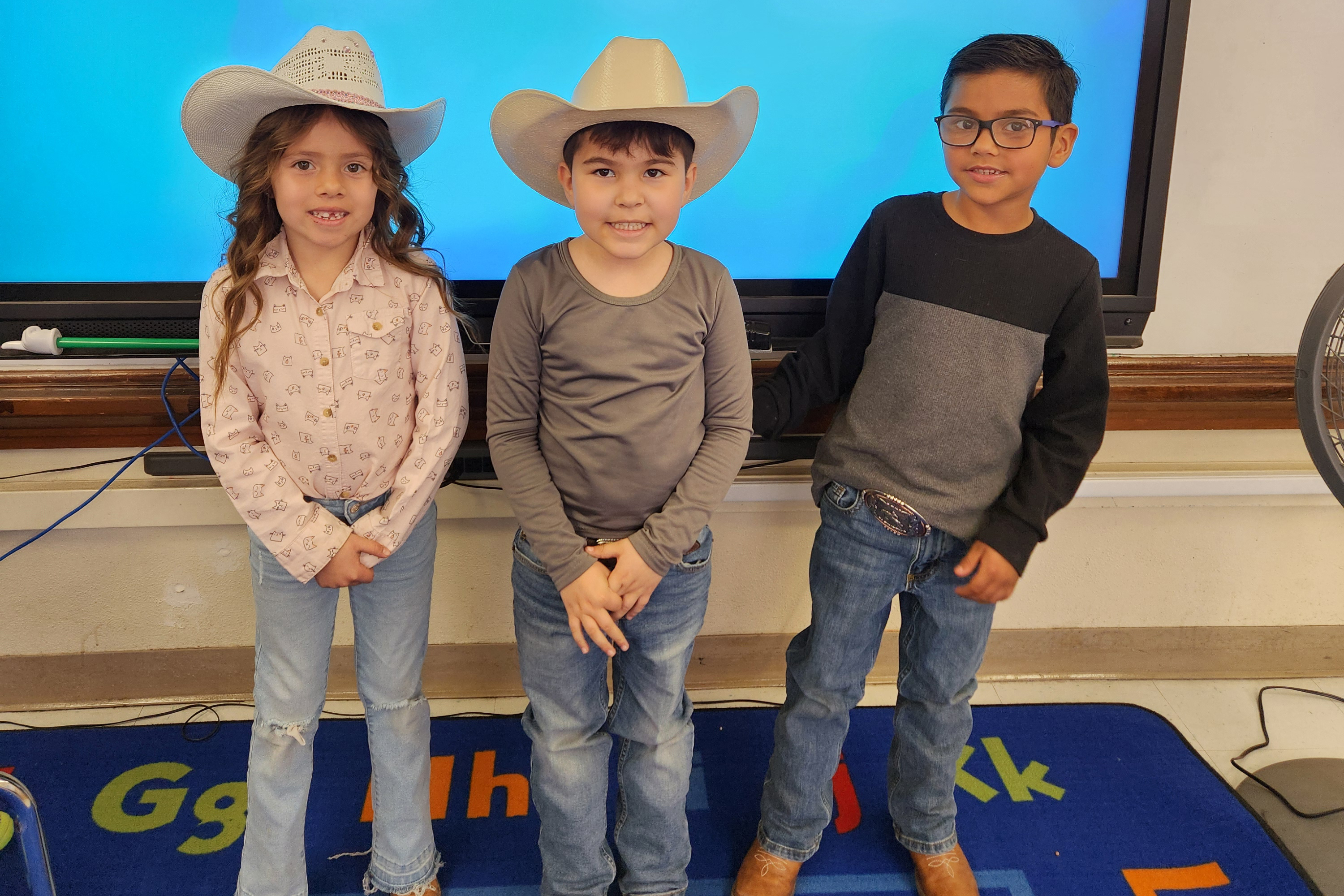 A little girl and two little boys show off their western wear