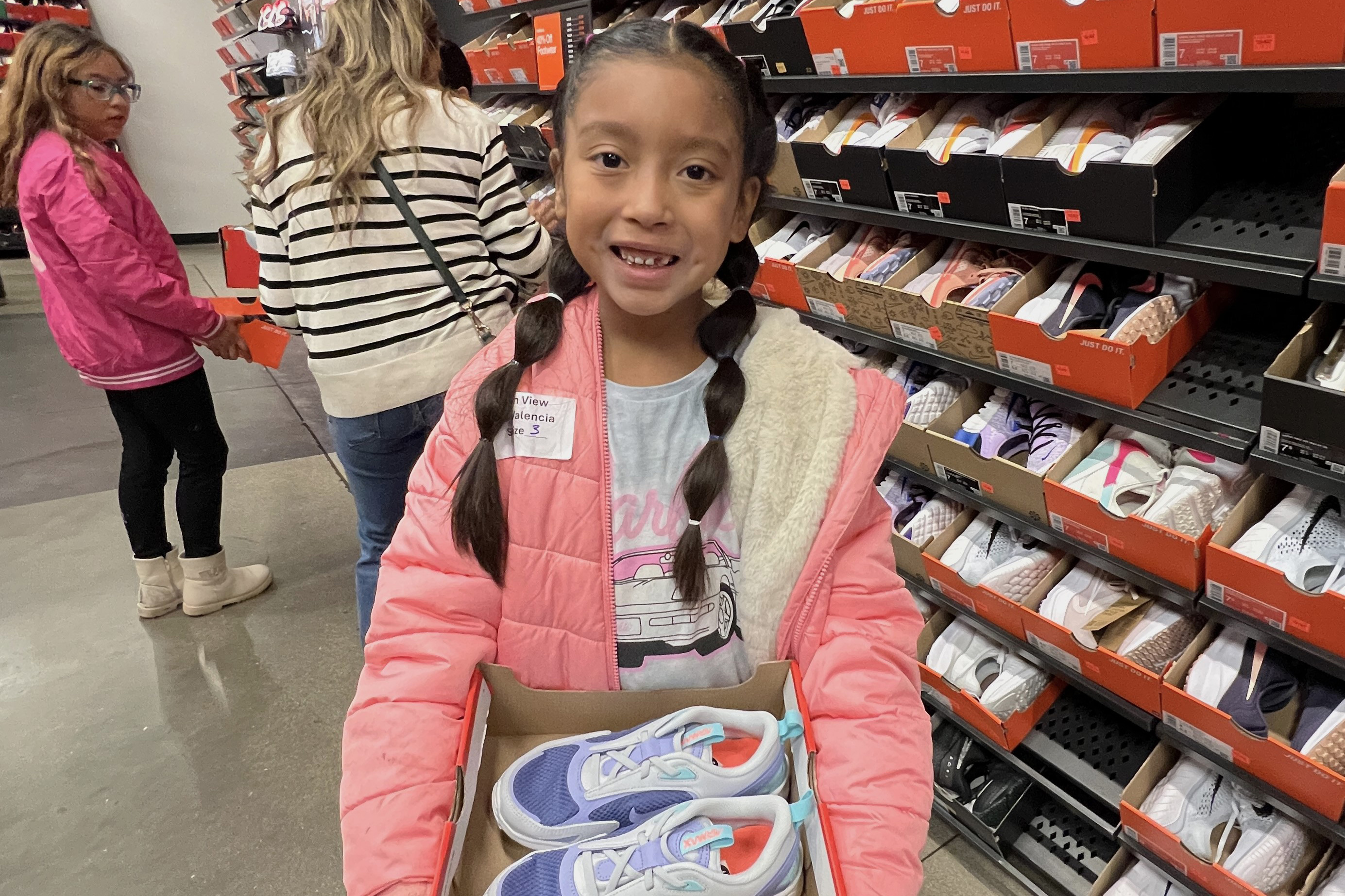 A little girl in a pink coat shows off her new pair of shoes!