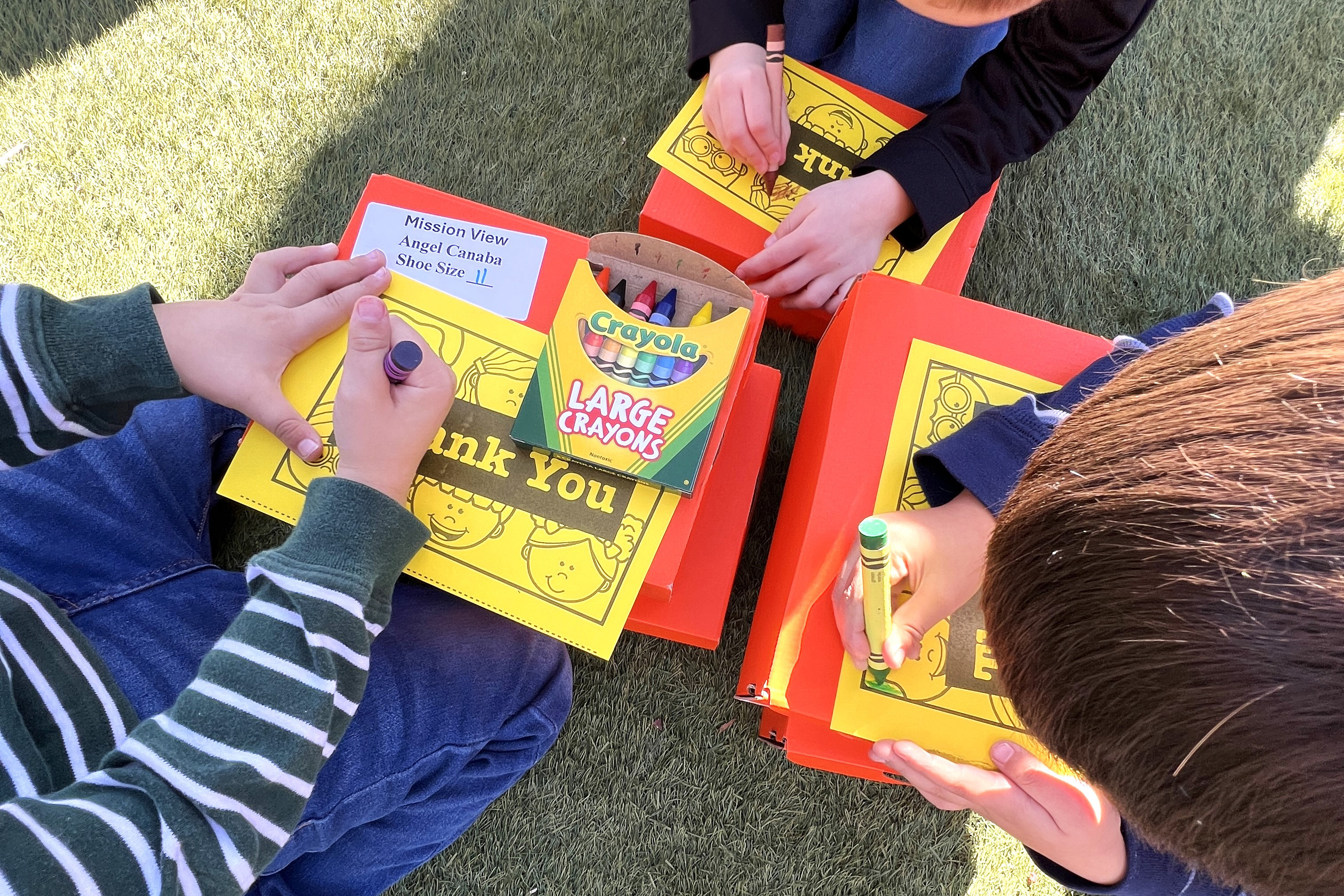 Three boys color Thank You notes with crayons