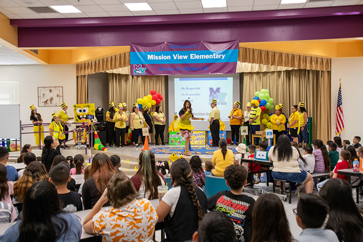 School staff dressed as bees perform for students during an assembly