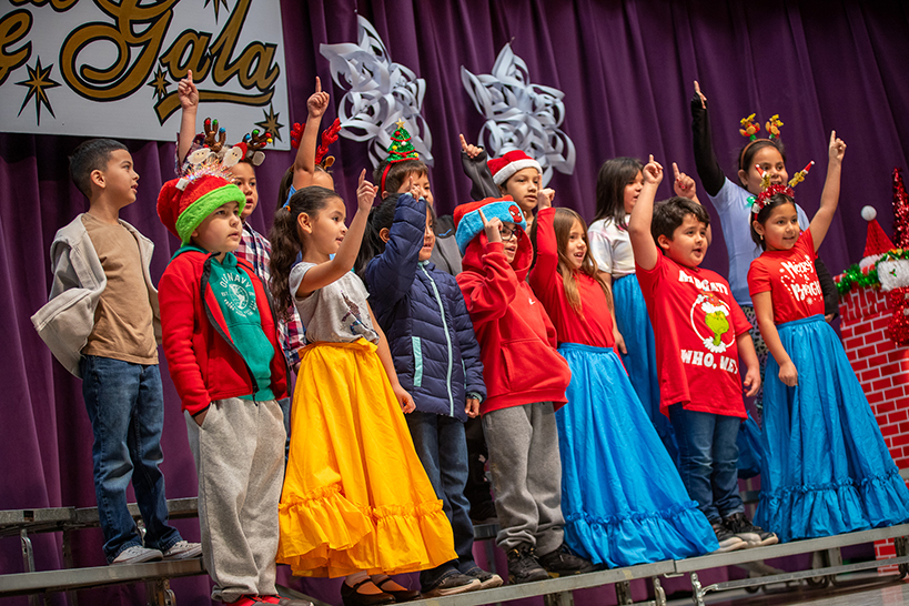 Students hold up their pointer finger as they sing