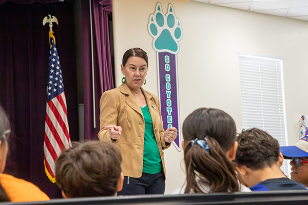 A woman points as she talks to students