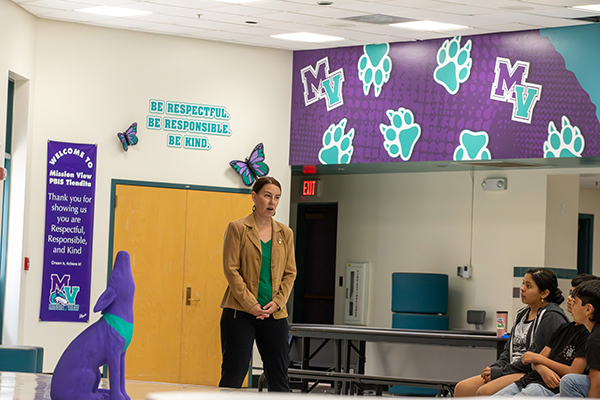A woman talks to students in the cafeteria