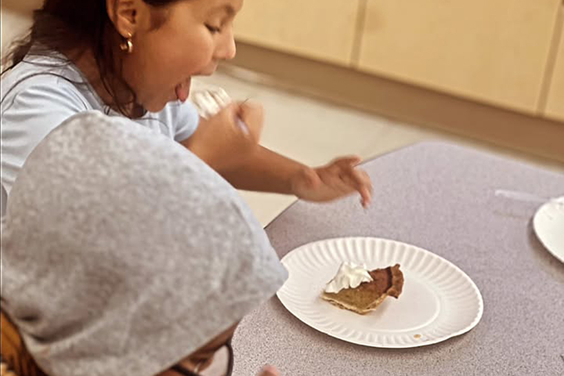 A girl spoons pumpkin pie into her mouth