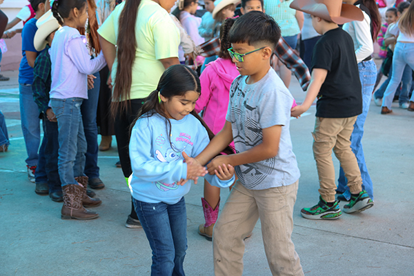 A girl and boy perform a square dance