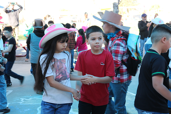 A girl and boy hold hands as they get ready to square dance