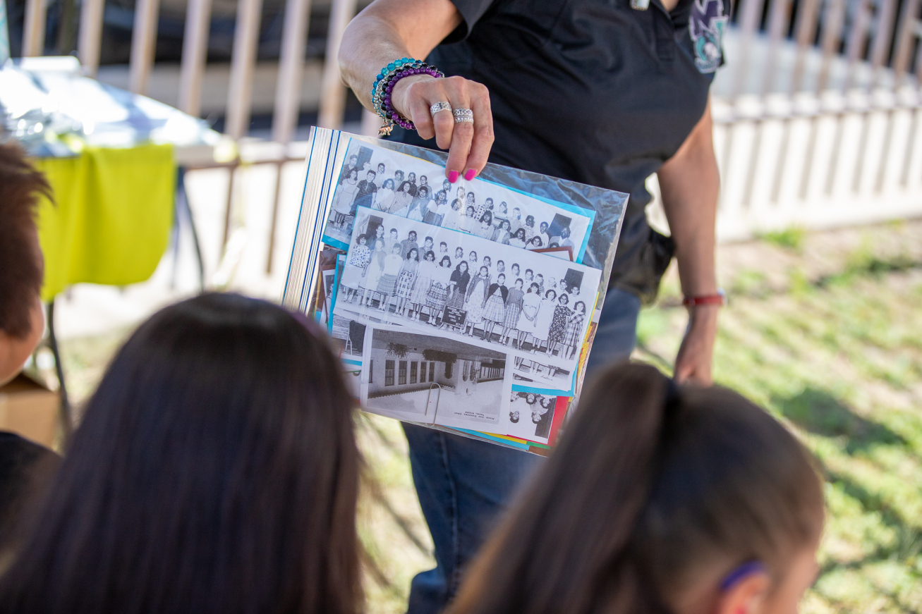 A teacher holds up some black and white photos of students who attended Mission View